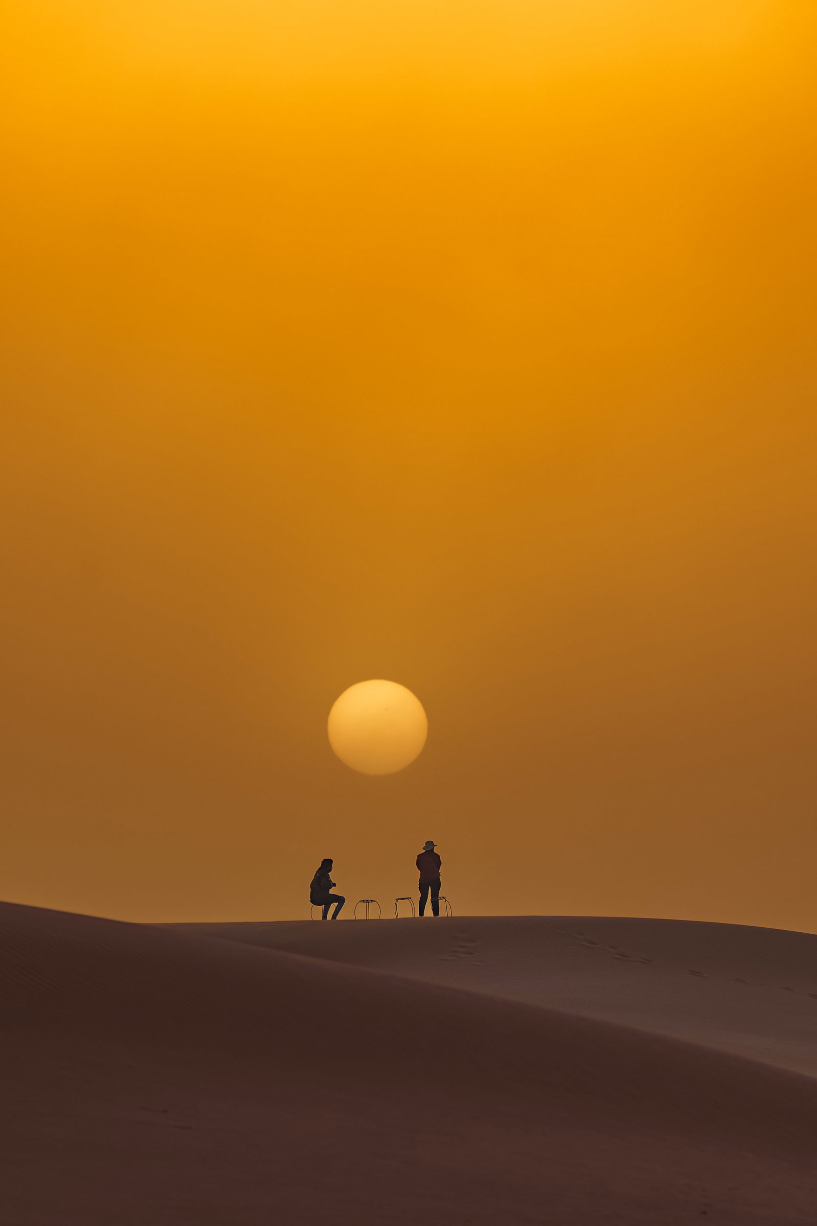 Camel caravan crossing the dunes at sunset